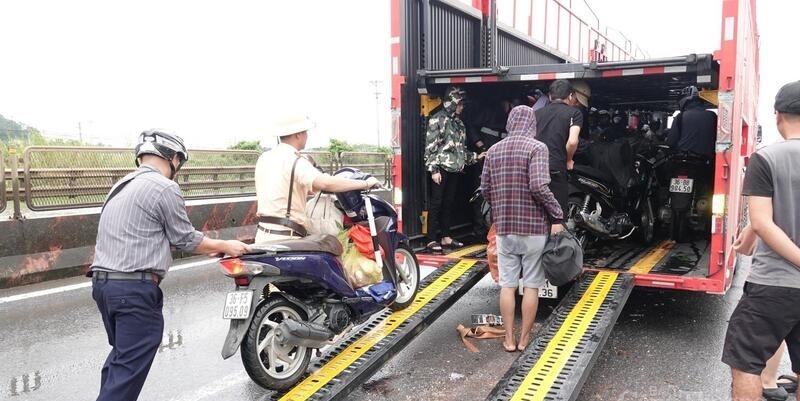 Nhiều xe tải qua đây đã dừng lại cùng lực lượng cảnh sát giao thông hỗ trợ đưa các phương tiện xe máy lên thùng xe để di chuyển qua các điểm ngập