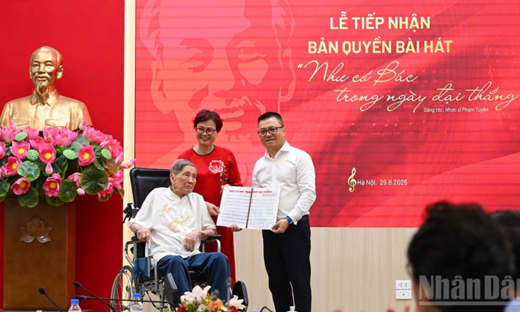 Tổng Biên tập Lê Quốc Minh nhận bản thảo bài hát Như có Bác trong ngày đại thắng có chữ ký đề tặng của nhạc sĩ Phạm Tuyên. Ảnh: nhandan.vn
