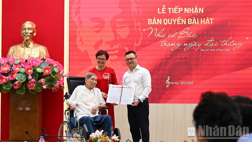 Tổng Biên tập Lê Quốc Minh nhận bản thảo bài hát Như có Bác trong ngày đại thắng có chữ ký đề tặng của nhạc sĩ Phạm Tuyên. Ảnh: nhandan.vn

