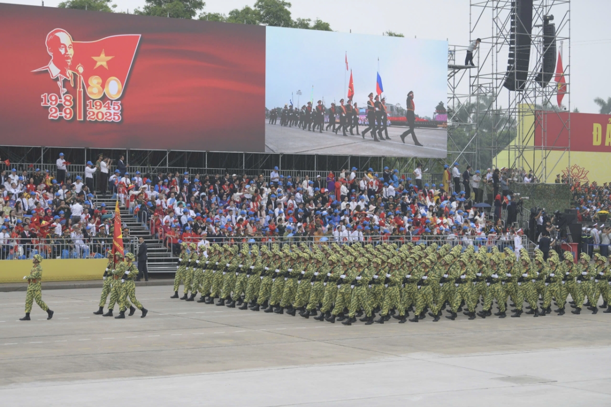 Đoàn quân tiến bước dưới quân kỳ.