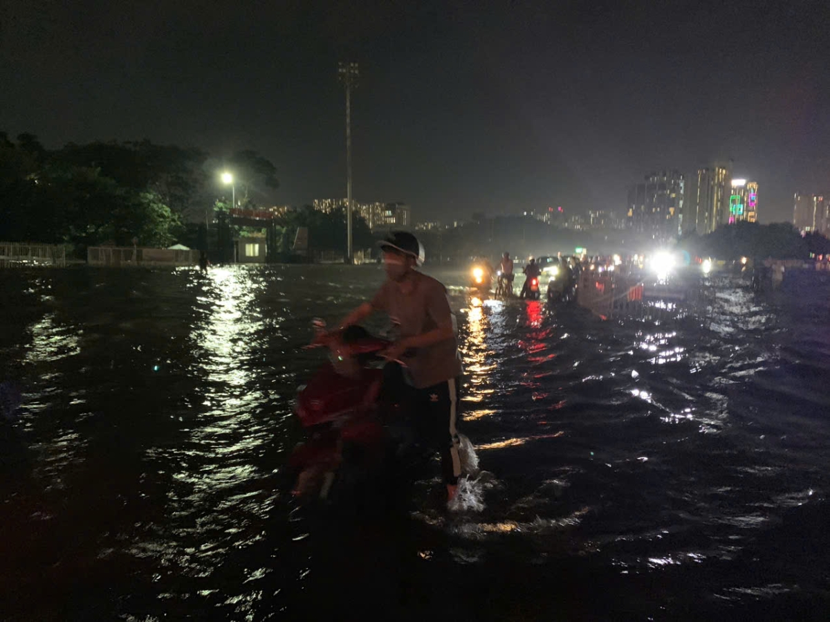Nhiều người mò mẫm dắt xe trong điều kiện đường ngập, thiếu ánh sáng do khu vực này đã bị cắt điện, không có đèn đường...