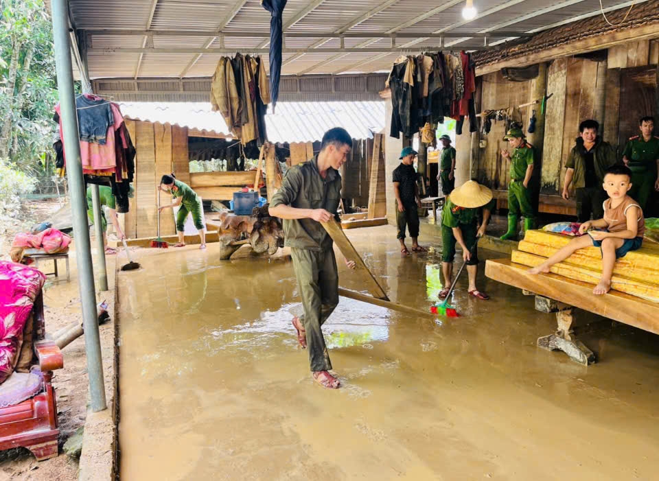 Lực lượng chức năng địa phương cùng các hộ dân dọn bùn đất trong sân nhà sau khi nước lũ rút.