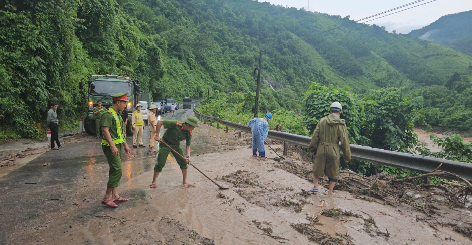 Các chiến sĩ cảnh sát giao thông dọn dẹp đất đá tràn ra đường sau sạt lở