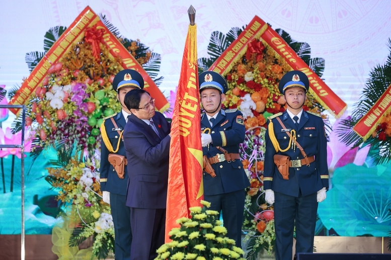Thủ tướng Phạm Minh Chính gắn huy hiệu Danh hiệu Anh hùng lực lượng vũ trang nhân dân lên Quân kỳ Quyết thắng của Quân chủng Phòng không - Không quân - Ảnh: VGP