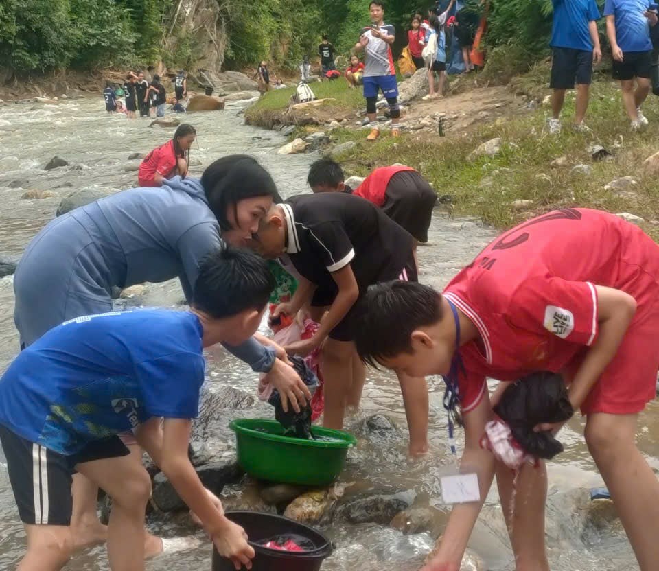 Cô giáo cẩn thận hướng dẫn học sinh tắm giặt an toàn bên suối Poong