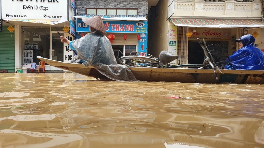 Nước ngập sâu, người dân sử dụng thuyền để di chuyển trong đô thị.