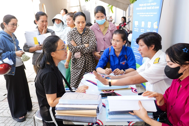 Cán bộ thuế tư vấn cho các hộ kinh doanh - Ảnh: Hữu Hạnh.