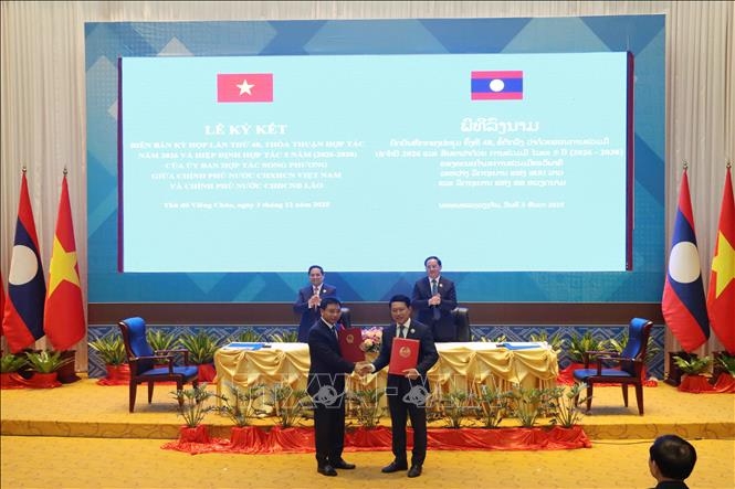 Chủ tịch Ủy ban hợp tác Việt Nam - Lào Nguyễn Văn Thắng và Chủ tịch Ủy ban hợp tác Lào - Việt Nam Saleumxay Kommasith trao đổi văn kiện hợp tác đã ký kết. Ảnh: TTXVN