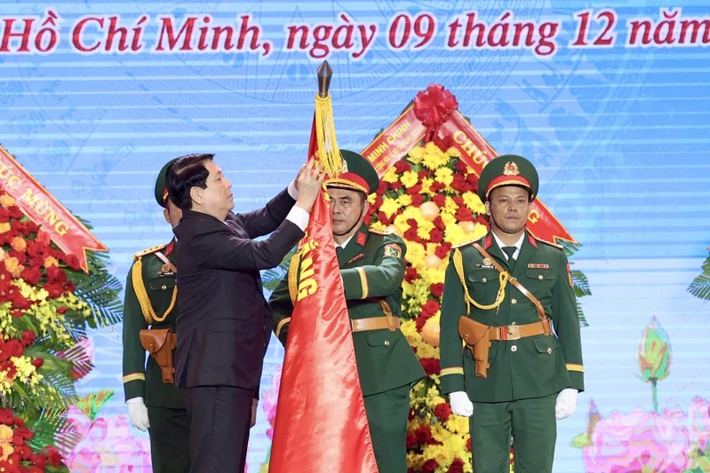 Chủ tịch nước Lương Cường gắn huy hiệu Anh hùng LLVT nhân dân lên Quân kỳ Quyết thắng Quân khu 7. Ảnh: Quân khu 7.