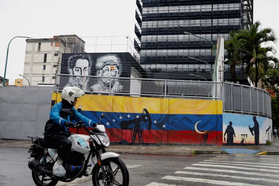 Một người đi xe máy chạy ngang bức tranh tường về Tập đoàn dầu khí quốc gia PDVSA của Venezuela gần trụ sở công ty tại Caracas, Venezuela. Nguồn ảnh: Leonardo Fernandez Viloria/Reuters