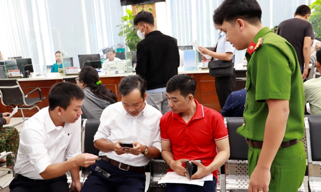 Cán bộ hướng dẫn người dân sử dụng dịch vụ công trực tuyến trên thiết bị điện tử.