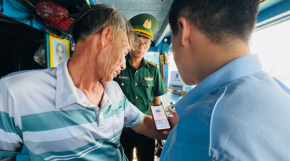 Lực lượng chức năng hướng dẫn ngư dân Quảng Ngãi cài đặt phần mềm eCDT VN. Ảnh: Nguyễn Ngọc