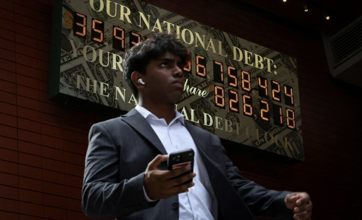 Một người đàn ông đi qua đồng hồ nợ công của Mỹ ở New York hôm 1/7/2025 - Ảnh: Reuters.
