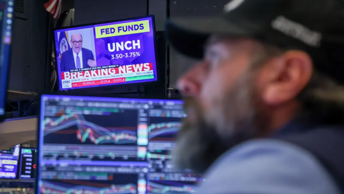 Một nhà giao dịch trên sàn NYSE ở New York làm việc cạnh màn hình đang phát bản tin về cuộc họp Fed ngày 28/1/2026 - Ảnh: Reuters.