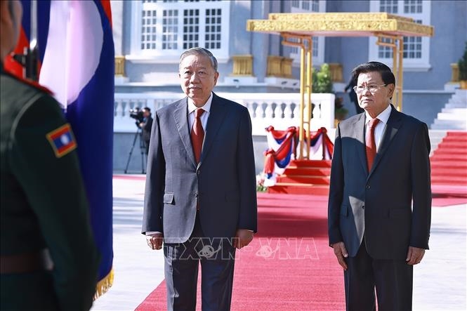 Tổng Bí thư Tô Lâm và Tổng Bí thư, Chủ tịch nước Lào Thongloun Sisoulith chào Quốc kỳ Lào, thực hiện nghi lễ duyệt Đội danh dự Quân đội nhân dân Lào. Ảnh: TTXVN
