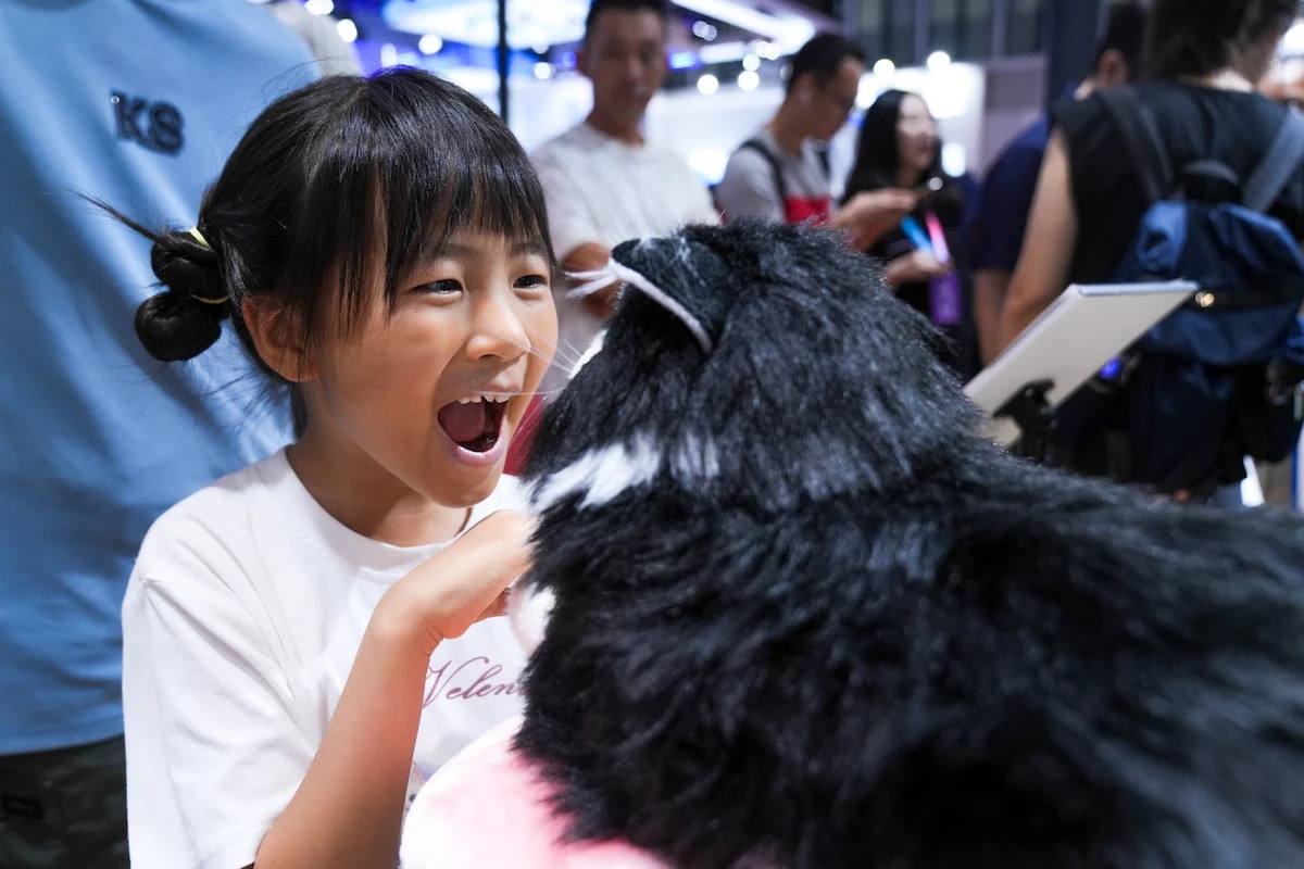 Một chú robot mô phỏng thú cưng thu hút sự chú ý của một bé gái trong Hội nghị Robot Thế giới (WRC) năm 2025 vào ngày 8 tháng 8 năm 2025 tại Bắc Kinh, Trung Quốc. Hội nghị WRC 2025 khai mạc vào ngày 8 tháng 8 tại Bắc Kinh đã hé lộ những xu hướng phát triển trong tương lai của robot thông minh có hình thể, tập trung vào các lĩnh vực như nhận thức, ra quyết định và an toàn.&nbsp;