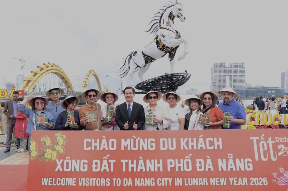 Phoa Giám đốc Sở Văn hóa, Thể thao và Du lịch Đà Nẵng Tán Văn Vương (người áo Vecton đứng giữa) chụp ảnh lưu niệm với khách quốc tế đến tham quan Cầu Rồng.