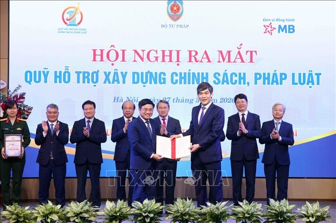 Đại diện các đơn vị đối tác trao văn bản bày tỏ ý định cam kết hỗ trợ cho Quỹ hỗ trợ xây dựng chính sách, pháp luật. Ảnh: TTXVN. 