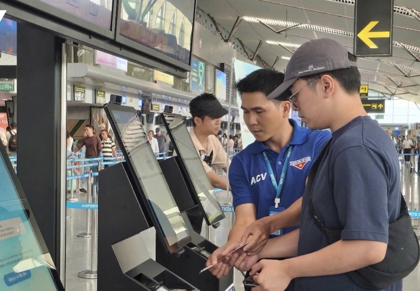 Nhân viên ACV (áo xanh) hướng dẫn hành khách thực hiện vận hành lối đi ưu tiên sử dụng sinh trắc học.