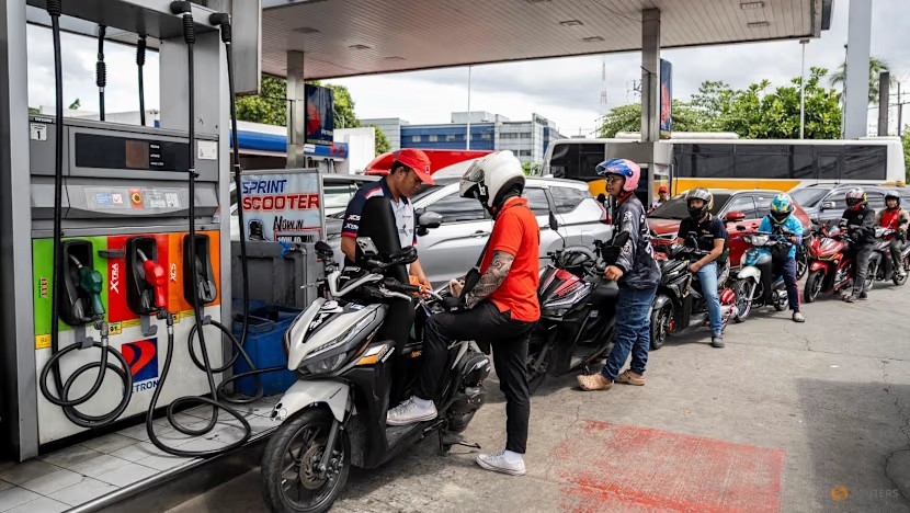 Nhân viên đổ xăng cho xe máy trong khi các tài xế xếp hàng tại một trạm xăng ở Quezon City, Metro Manila, Philippines. Ảnh: Reuters/Lisa Marie David