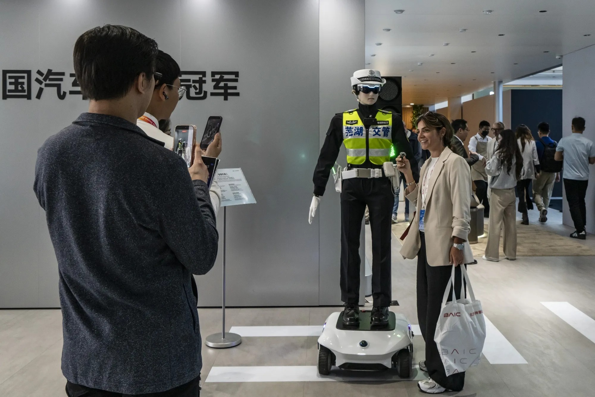 Khách tham dự chụp ảnh cùng robot điều khiển giao thông hình người tại Triển lãm Ô tô Bắc Kinh. Ảnh: Bloomberg