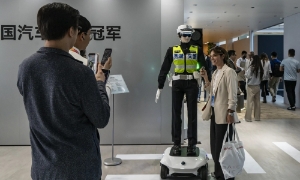 Khách tham dự chụp ảnh cùng robot điều khiển giao thông hình người tại Triển lãm Ô tô Bắc Kinh. Ảnh: Bloomberg
