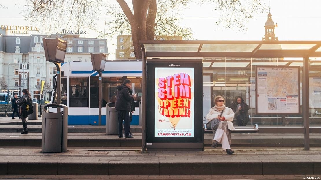 Một bảng quảng cáo phát sáng tại nhà chờ xe buýt ở Amsterdam hiển thị poster quảng bá, trong khi hành khách đứng chờ gần đó. Ảnh: JCDecaux