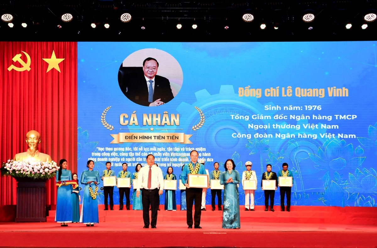 Đồng chí Nguyễn Phi Long - Ủy viên Ban chấp hành Trung ương Đảng, Phó Bí thư Thường trực Đảng ủy Mặt trận Tổ quốc các đoàn thể Trung ương, Phó Chủ tịch Ủy ban Trung ương Mặt trận Tổ quốc Việt Nam (bên trái) trao hoa chúc mừng và đồng chí Thái Thu Sương - Phó Chủ tịch thường trực Tổng Liên đoàn Lao động Việt Nam (bên phải) trao bằng khen cho đồng chí Lê Quang Vinh.