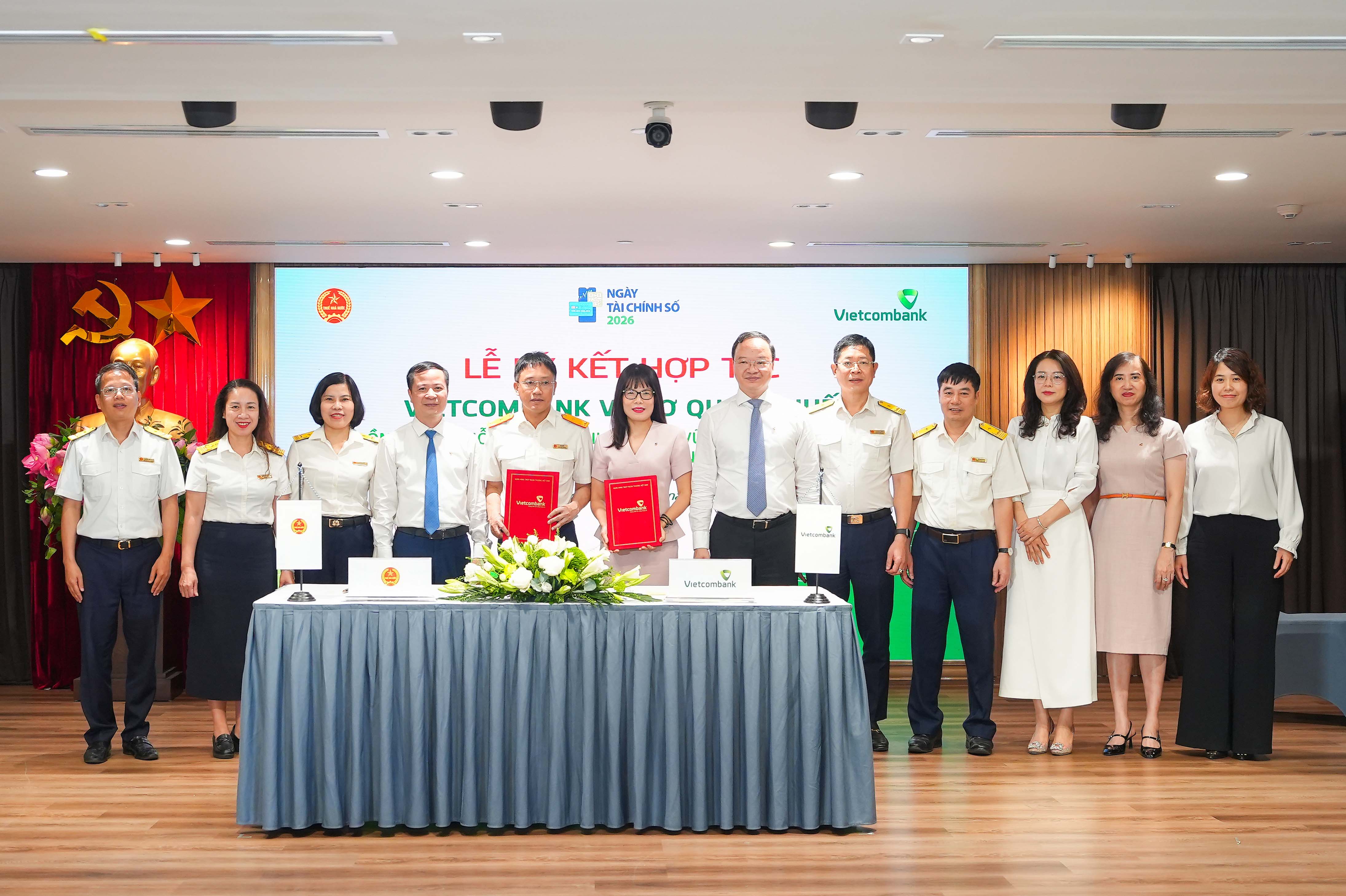 Ông Mai Sơn - Phó Cục Trưởng Cục Thuế (thứ 5, từ trái sang) và bà Đoàn Hồng Nhung - Giám đốc Khối Bán lẻ, Thành viên Ban điều hành Vietcombank (thứ 6, từ trái sang) thực hiện nghi thức ký kết và trao biên bản Thỏa thuận Hợp tác giữa Cục Thuế và Vietcombank dưới sự chứng kiến của đại diện lãnh đạo hai đơn vị. Ảnh: VCB.