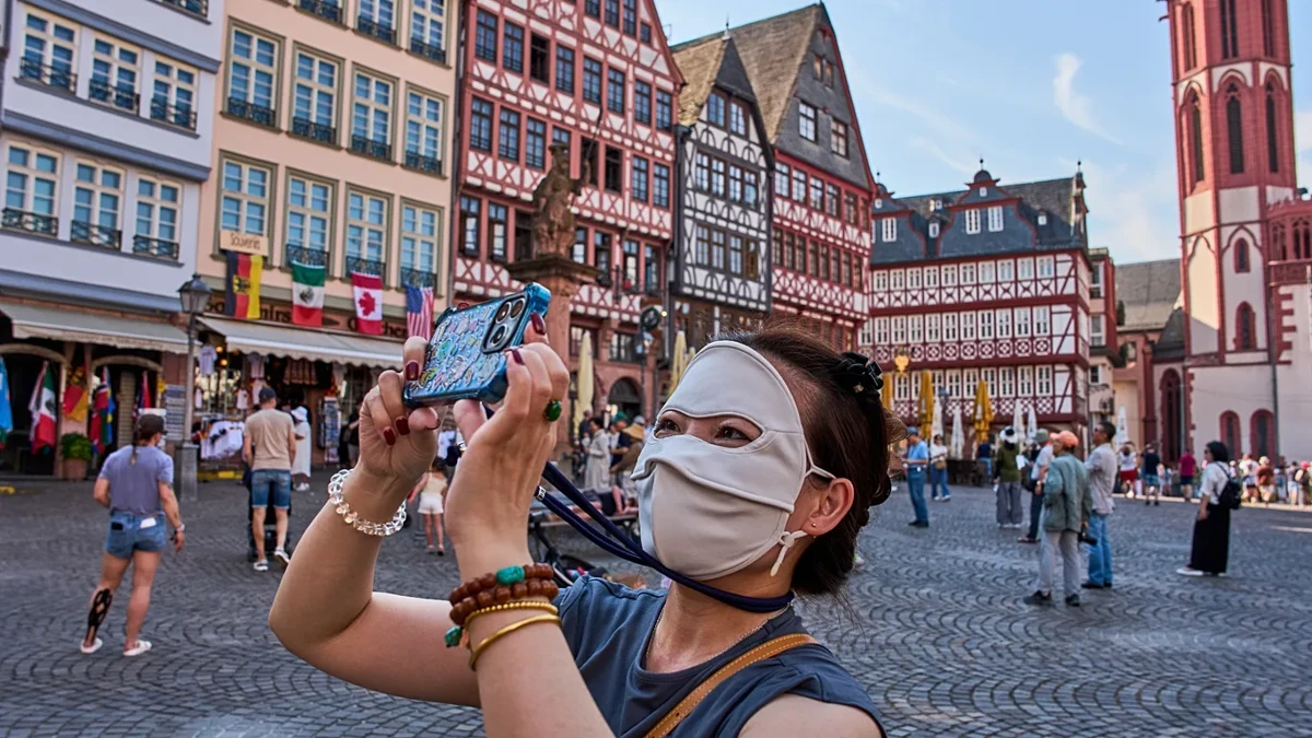 Một du khách đến từ Trung Quốc đang chụp ảnh tại quảng trường Römerberg ở Frankfurt. Ảnh: AP