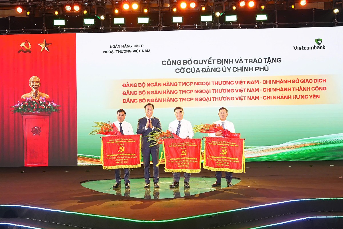 Đại diện Đảng ủy Chính phủ,đồng chí Lại Xuân Lâm - Phó Bí thư Chuyên trách trao cờ và tặng hoa cho đại diện 3 Đảng bộ trực thuộc Vietcombank được công nhận đạt tiêu chuẩn hoàn thành xuất sắc nhiệm vụ tiêu biểu giai đoạn 2021-2025, gồm: Đảng bộ Chi nhánh Sở Giao dịch, Chi nhánh Thành Công và Chi nhánh Hưng Yên. Ảnh: Vietcombank.