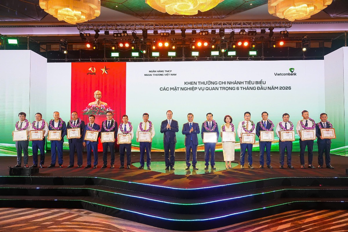 Đồng chí Nguyễn Thanh Tùng - Bí thư Đảng ủy, Chủ tịch HĐQT Vietcombank (thứ 8 từ phải sang) tặng giấy khen và đ/c Lê Quang Vinh - Phó Bí thư Đảng ủy, Thành viên HĐQT, Tổng Giám đốc Vietcombank (thứ 9 từ phải sang) trao hoa chúc mừng cho 15 chi nhánh tiêu biểu trong hoạt động kinh doanh 6 tháng đầu năm 2026. Ảnh: Vietcombank.