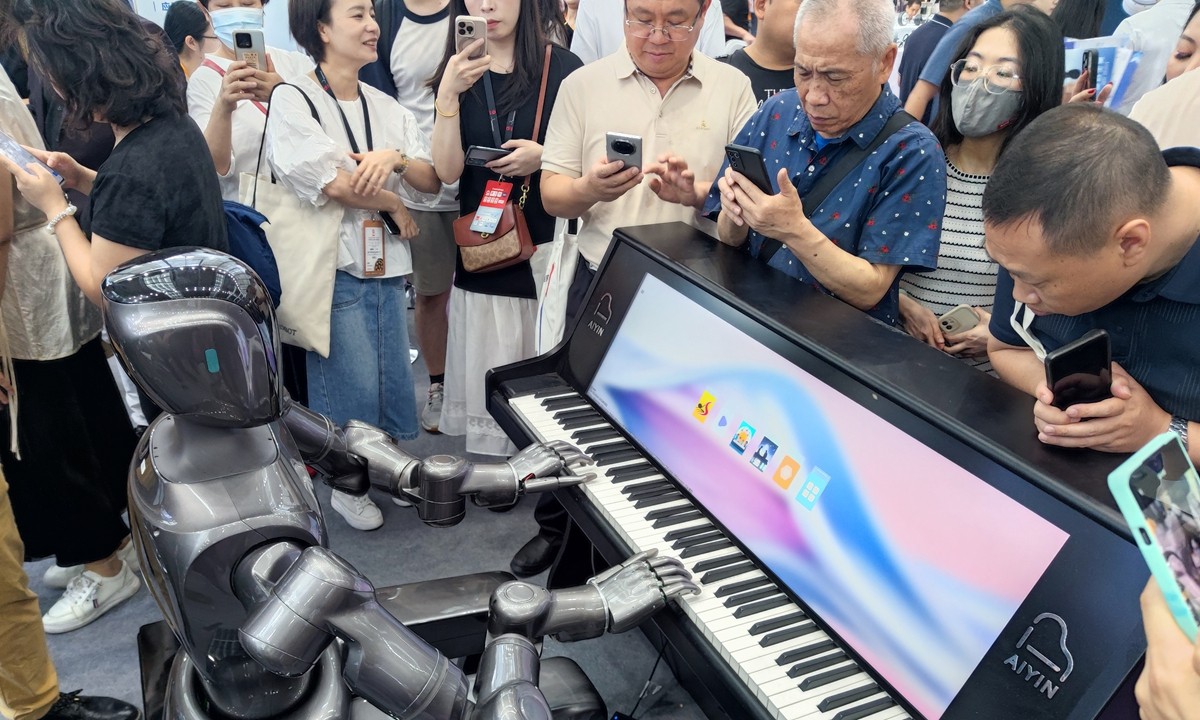 Người dân xem một robot hình người chơi piano tại Thâm Quyến, tỉnh Quảng Đông, miền Nam Trung Quốc. Ảnh: VCG