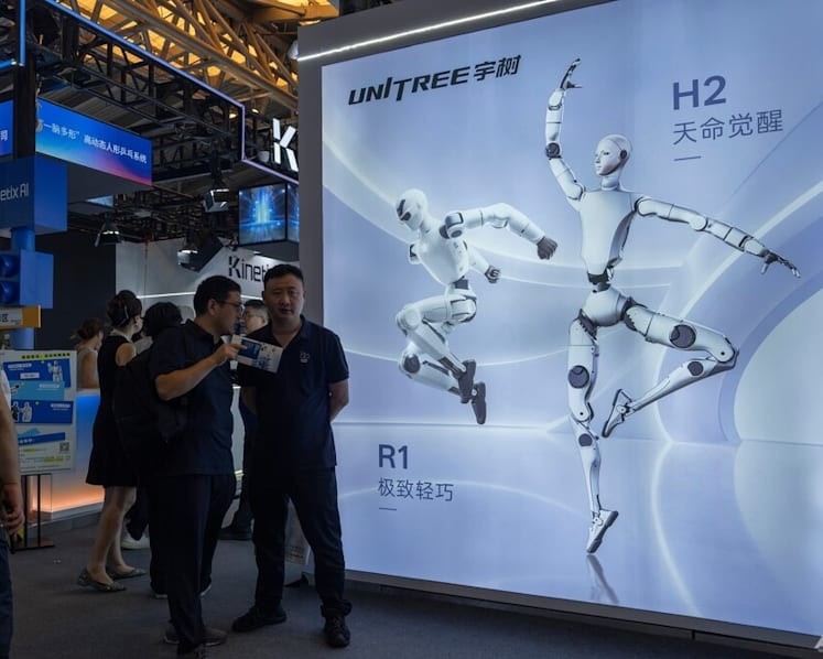 Khách tham quan đứng gần quảng cáo của Unitree Robotics, một công ty robot hình người thương mại hàng đầu của Trung Quốc, tại Hội nghị Trí tuệ nhân tạo thế giới - 2026 ở Thượng Hải, Trung Quốc. Ảnh: AP/Ng Han Guan.