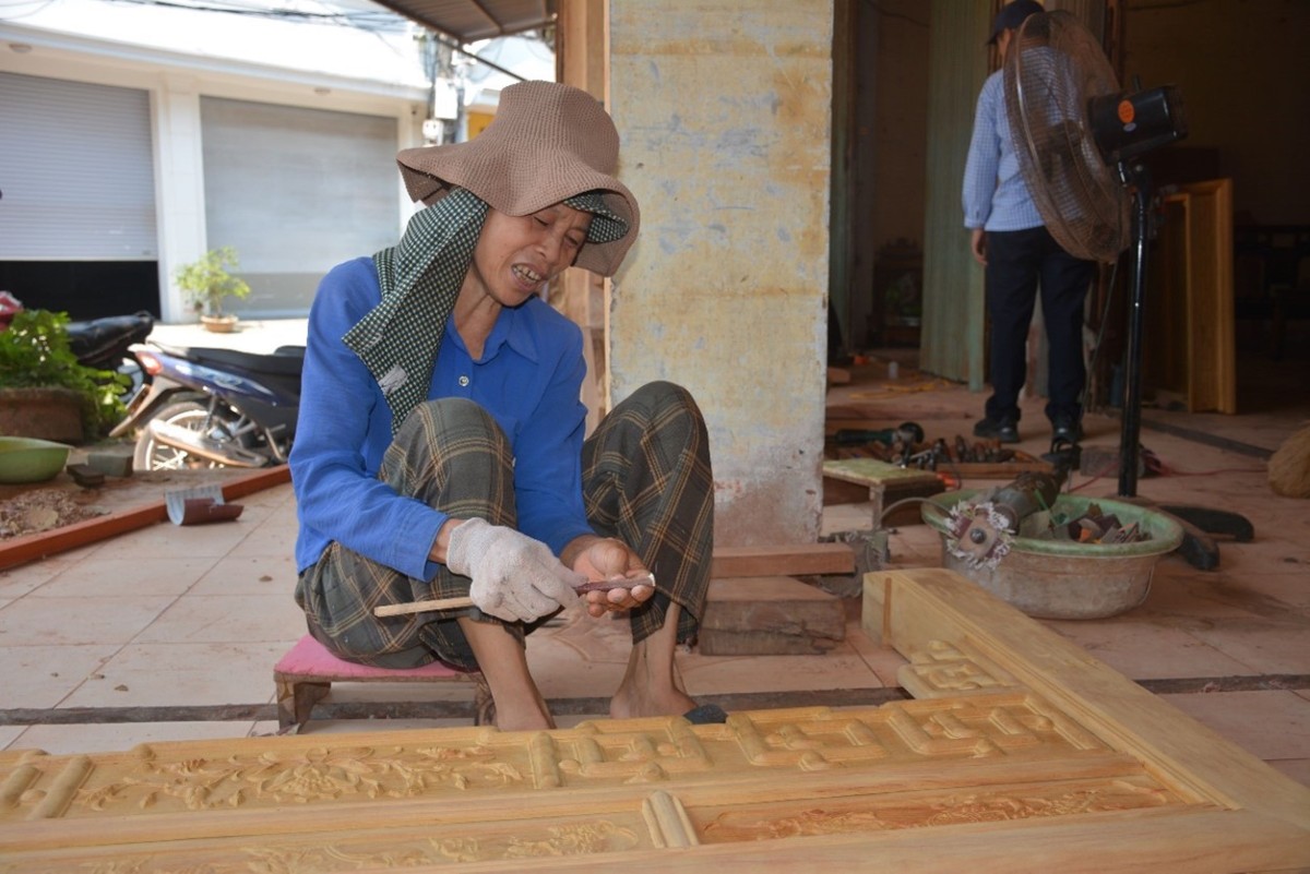 Bà Dương Thị Thuỷ đang đục chạm trên sản phẩm gỗ. Ảnh: Chu Khôi.