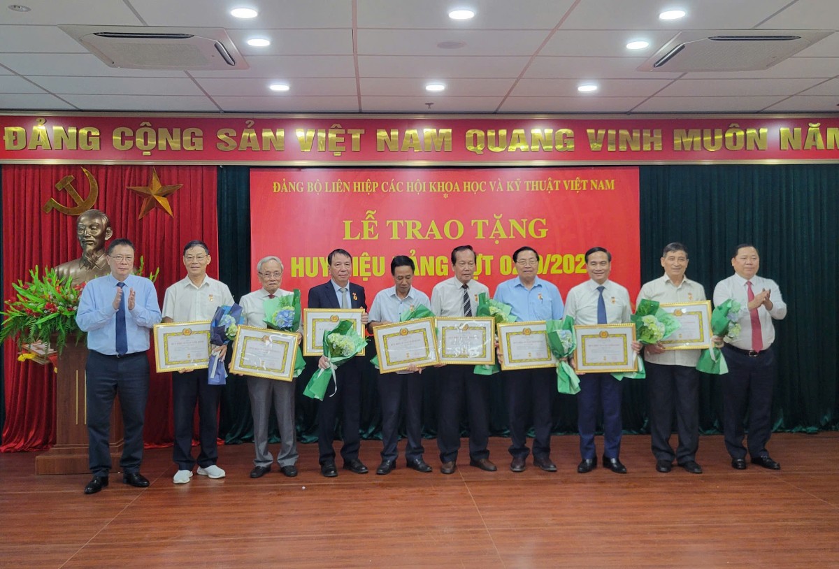 Phó Bí thư Thường trực Đảng ủy Mặt trận Tổ quốc, các đoàn thể Trung ương Nguyễn Phi Long (ngoài cùng bên phải) và GS.VS Châu Văn Minh, Phó Chủ tịch không chuyên trách Ủy ban Trung ương Mặt trận Tổ quốc Việt Nam, Bí thư Đảng ủy, Chủ tịch Liên hiệp các Hội Khoa học và Kỹ thuật Việt Nam (ngoài cùng bên trái) trao Huy hiêu Đảng và tặng hoa các đồng chí đảng viên. Ảnh: Vusta.