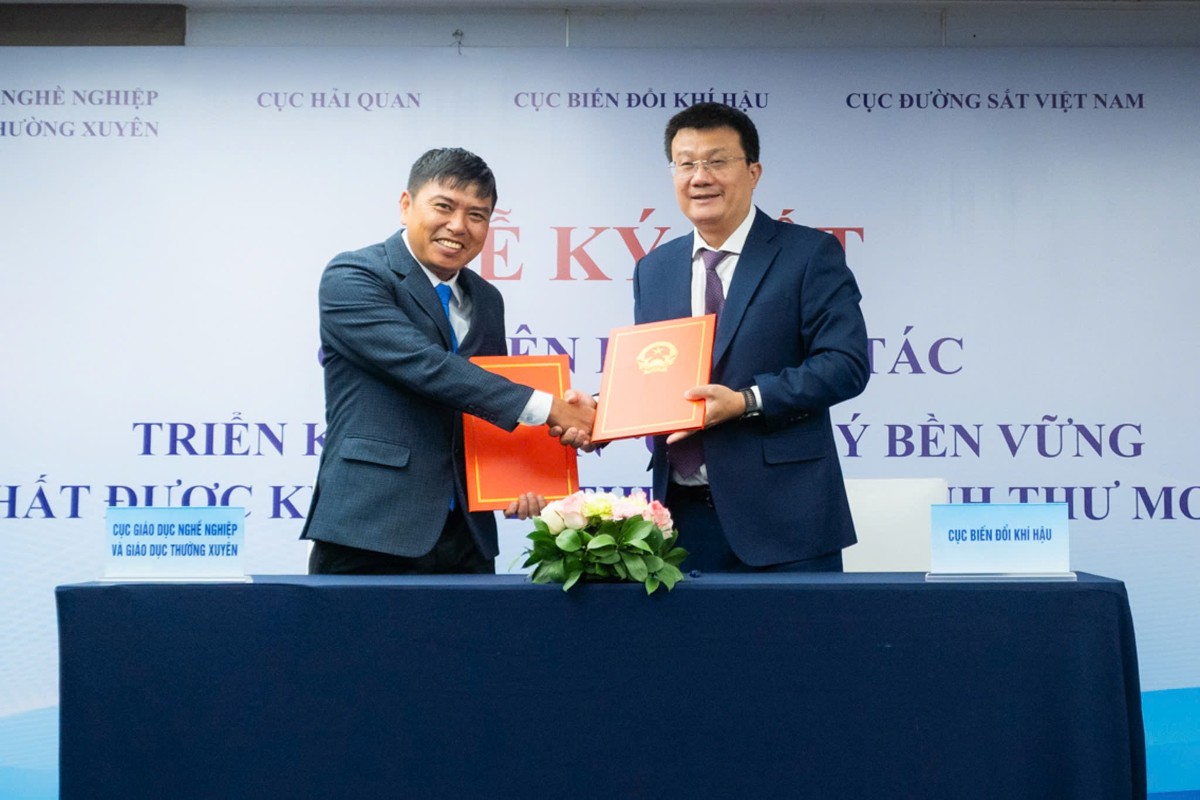 Ông Nguyễn Tuấn Quang, Cục trưởng Cục Biến đổi khí hậu (bên phải) và ông Phạm Vũ Quốc Bình, Phó Cục trưởng Cục Giáo dục nghề nghiệp và Giáo dục thường xuyên (bên trái), trao biên bản hợp tác giữa hai cơ quan.