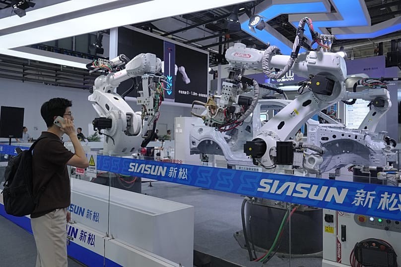 Khách tham quan quan sát các cánh tay robot phục vụ sản xuất công nghiệp tại Hội nghị Robot thế giới ở Bắc Kinh 2026. Ảnh: AP Photo/Andy Wong.