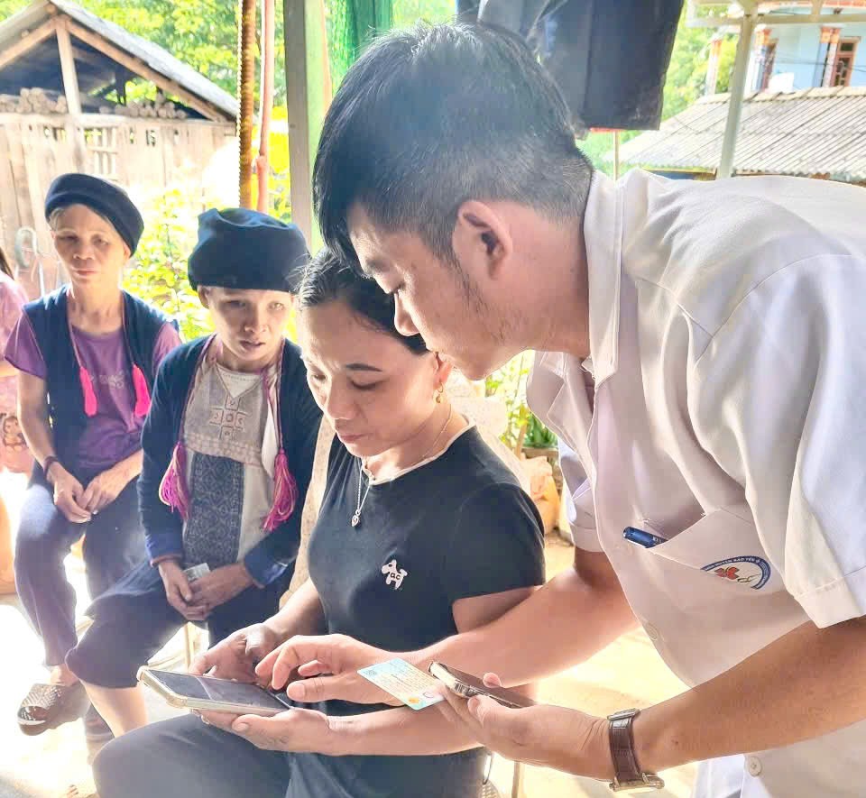 Cán bộ trạm y tế hỗ trợ cài đặt Sổ sức khỏe điện tử trên ứng dụng VNeID cho người dân. Ảnh: Sở Y tế Lào Cai.