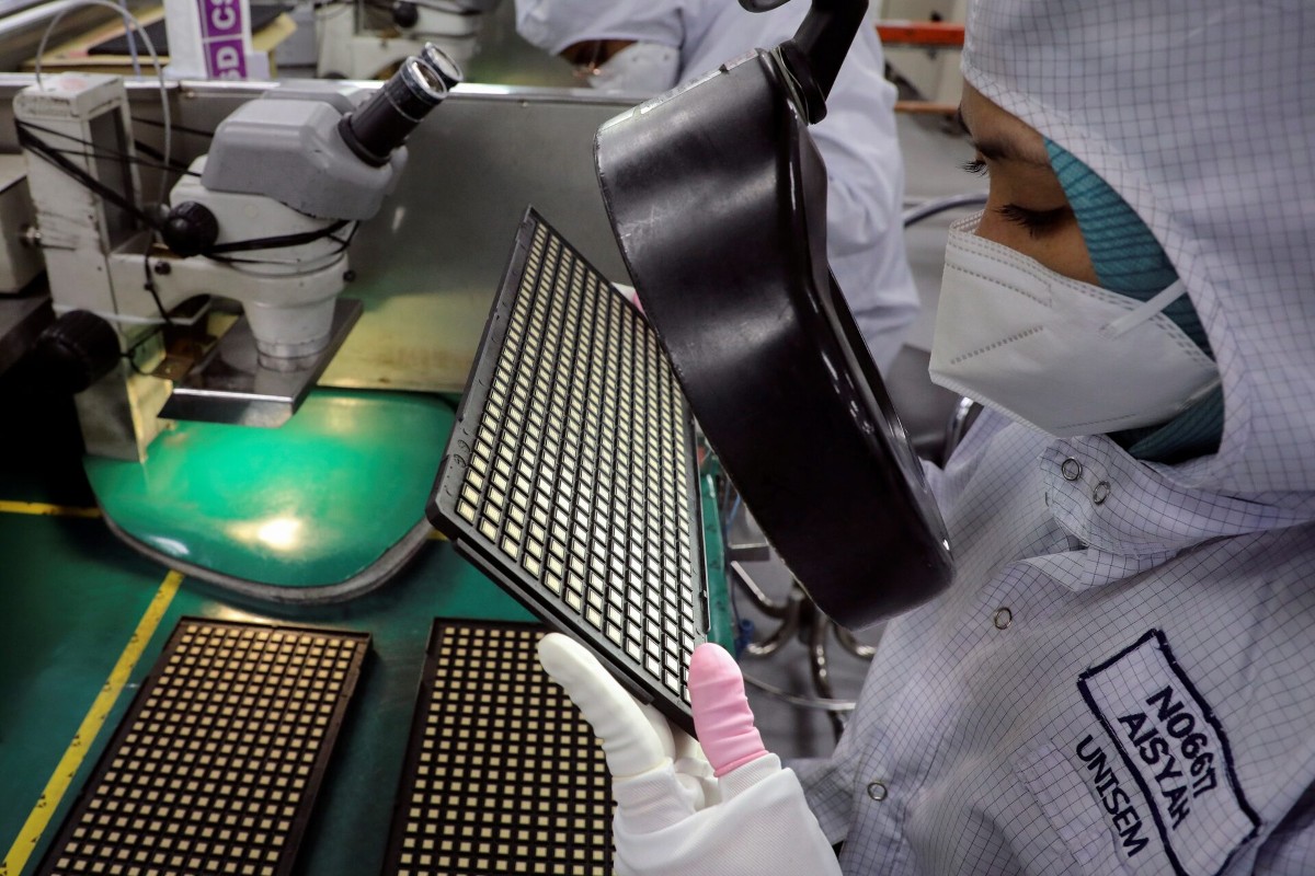 Một công nhân kiểm tra chip tại Malaysia. Ảnh: Reuters.
